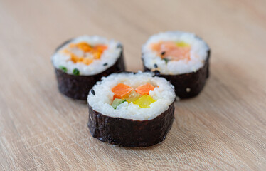Three rolls of sushi on a wooden background