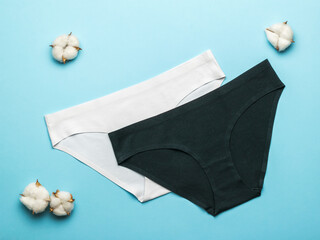 Black and white women's panties with cotton on a blue background. Flat lay.