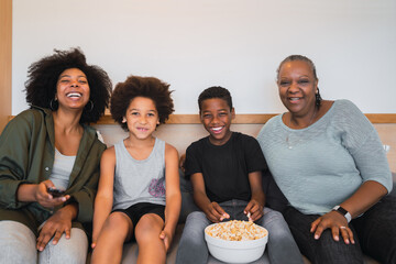 Grandmother, mother and children watching a movie at home.