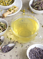 Chamomile herbal tea in glass cup and jar with dry herb flowers, above overhead view, naturopathy, natural medicine, healing drinks for sleep, skin and hair care concept