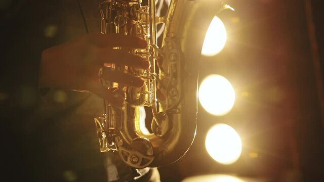 Saxophonist play on golden saxophone. Music. Live performance. Silhouette of young male saxophonist musician playing golden alt saxophone on musical instrument.
