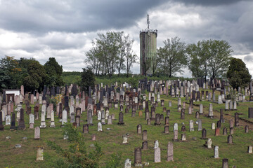 Cemetery on the hillside in front of the transmission tower; color photo.