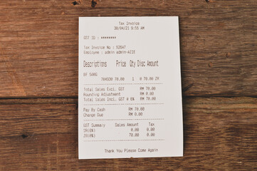 Paper sales receipt isolated on a wooden background