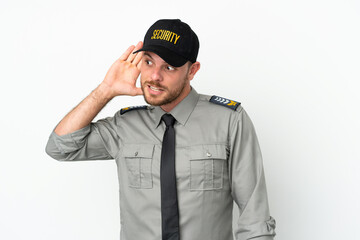 Young security Brazilian man isolated on white background listening to something by putting hand on the ear