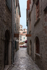 Fototapeta premium Narrow street with ancient stone pavers with medieval buildings in old european city Kotor in Montenegro