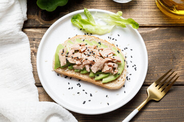 Avocado, canned tuna and boiled egg toast on wooden table background. Healthy food, avocado open sandwich for breakfast or lunch. Flat lay, top view, close up