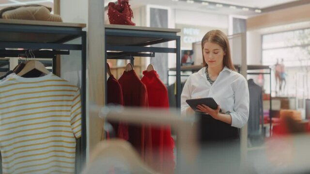 Clothing Store: Female Visual Merchandising Professional Uses Tablet Computer To Create Stylish Collection. Fashionable Shop Sales Retail Assistant Checks Stock. Small Business Owner Orders Items