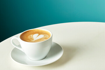 Traditional morning coffee cappuccino in a mug on a turquoise background, place for text