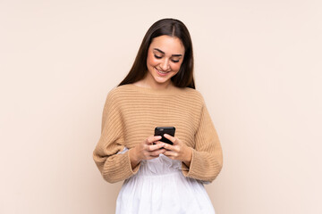 Young caucasian woman isolated on beige background sending a message with the mobile