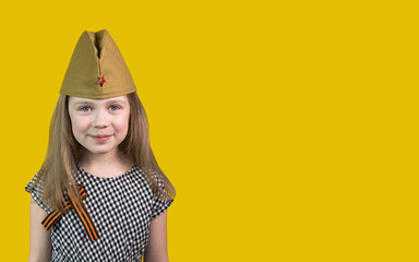 9th May. A little girl in a garrison cap with a St. George ribbon stands on a yellow background and...