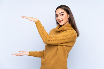 Young caucasian woman isolated on blue background holding copyspace to insert an ad