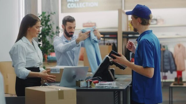 Clothing Store Checkout Cashier Counter: Female and Male Retail Sales Managers Carefully Packing Online Ordered Clothes into Boxes. Fashionable Shop, with Stylish Brand Designs Available on Internet