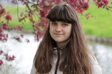 close up smiling caucasian portrait of girl, young woman outdoor, red blossom tree background in the Netherlands