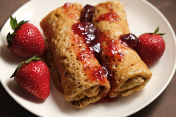 Pancakes rolls poured strawberry jam and decorated fresh strawberries.
