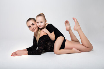 Fototapeta na wymiar mom flexes in gymnastic position daughter hugs mom