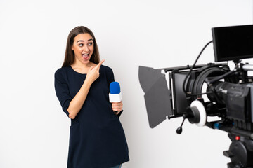 Reporter woman holding a microphone and reporting news isolated on white background surprised and...