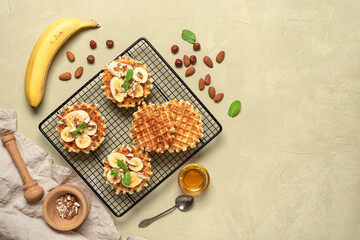 Homemade Belgian waffles with banana, nuts and honey. Beige concrete background. Top view, flat lay.