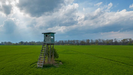 ein Hochsitz auf einer Wiese vor bewölktem Himmel