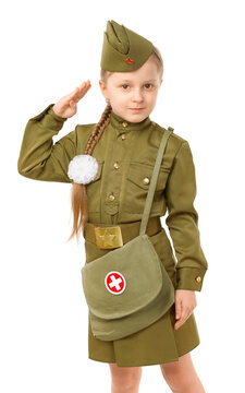 A little girl with a long pigtail and a white bow in a Soviet military nurse's uniform salutes on a white background. Concept for the Victory Day in World War II on May 9