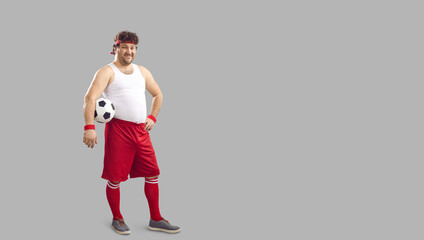 Happy fat man holding soccer ball under arm. Full body funny smiling chubby male football player in...