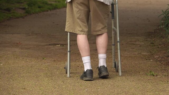 Senior man walking in the park using a walker has trouble with uneven ground - trip hazard