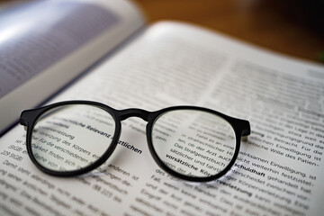 Black framed reading  glasses  on the book, close up