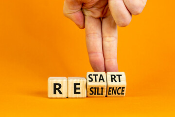 Restart and resilience symbol. Businessman turns cubes and changes the word 'restart' to 'resilience'. Beautiful orange background. Business and restart - resilience concept. Copy space.