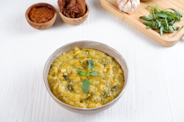 Bubur Manado or Tinutuan porridge. Indonesian food - Manado traditional rice porridge, mixed with pumpkin, corn, vegetables. Served with salted fish and sambal or chili sauce