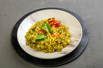 Food for suhoor in Ramadan bulgur post with vegetables in a plate on a gray background.