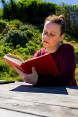 Fototapeta premium Mujer joven senatada en el parque leyendo un libro