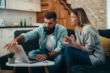 Couple using a laptop for paying bills online together at home