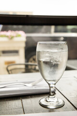 A water glass and a silverware setting on a wood table at a high end restaurant