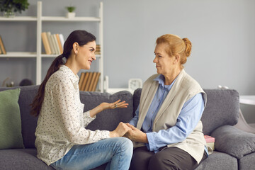 Grown-up daughter talking to senior mother. Happy daughter and friendly mother-in-law sitting on...