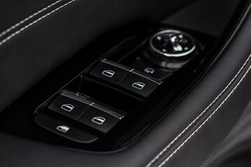 Close up view of button controlling window in modern car interior. Vehicle interior detail. Door handle with windows controls