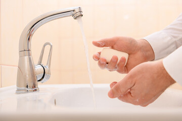 hand washing with soap or gel under running water in the washbasin, cleanliness and hygiene, men's...
