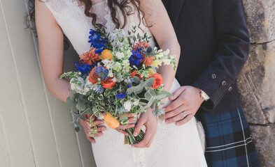 Close up of brides hands holding bouquet with groom