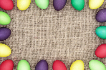 Multicolored Easter eggs on a burlap background. Easter frame.