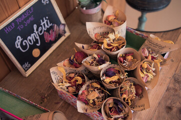 Rose petal dried confetti on cones close up with blackboard sign at a wedding 