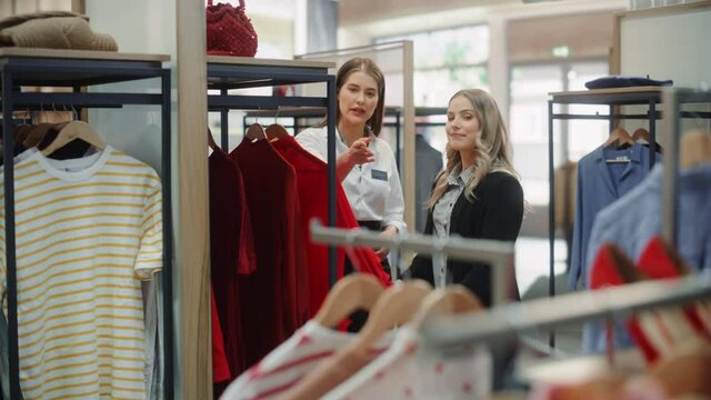 Clothing Store: Professional Sales Associate Talks with Beautiful Female Customer, Shopping Stylish Clothes, Choosing Trendy, Sustainable Brands. Small Business Owner and Designer Talking to Client