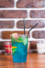 Cold citrus lemonade in a plastic cup on a wooden table