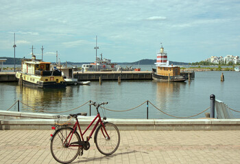 Lahti city in Finland. The embankment of the bay in warm sunshine. Marina of ships, residential buildings, parked bike. Travel on bicycle