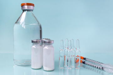 Medicines in vials and ampoules, undiluted and liquid for injections, syringes for injections on a mint background 