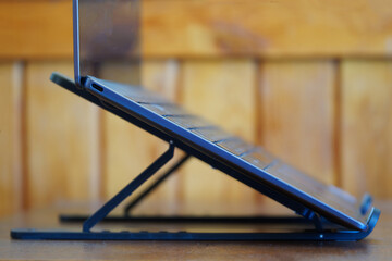 A modern slim silver laptop or ultrabook mounted on a portable holder stand against a wooden...