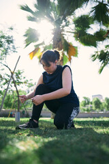   A beautiful white woman with brown hair and a sports outfit fastens the laces of her sneakers before exercising in a park near the city of Santiago de Chile