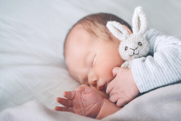 Newborn sleep at first days of life. Portrait of new born baby one week old with cute soft toy in...