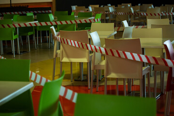 the food court of the shopping center is closed for quarantine, due to threat of coronavirus, access to restaurant, cafe is prohibited for duration of pandemic, seats are blocked with a warning tape