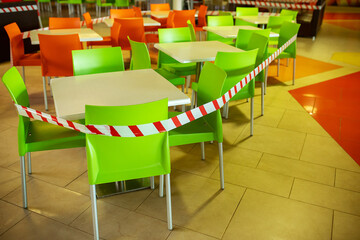 the food court of the shopping center is closed for quarantine, due to threat of coronavirus, access to restaurant, cafe is prohibited for duration of pandemic, seats are blocked with a warning tape