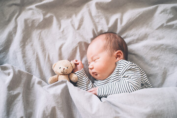 Newborn sleep at first days of life. Portrait of new born baby one week old with cute soft toy in...