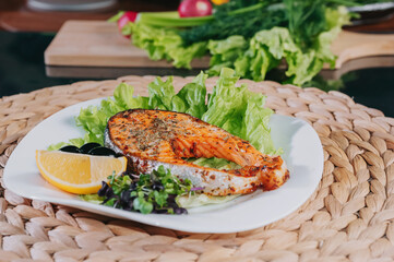 Cooked trout steak on a plate with herbs and vegetables