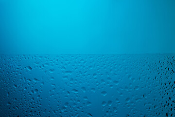 Water drops on glass in blue light.